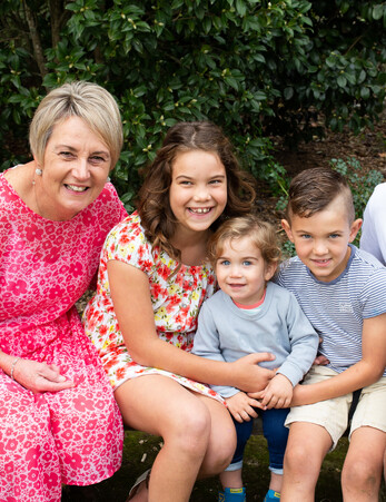 Grandmother smiles next to her three young grandchildren