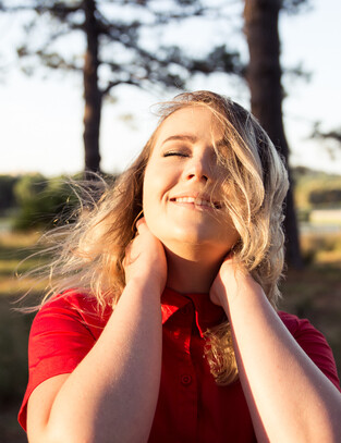 Girl poses for image, eyes shut as the evening sun warms her face and golden hair