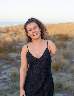 Girl poses for image on the beach with a big smile on her face