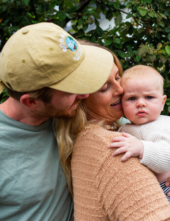 Young people look lovingly at their baby who they're holding