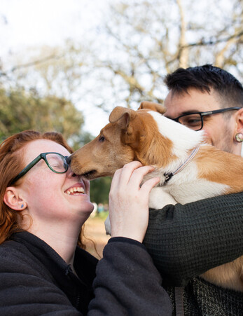Young couple laugh and smile while holding their dog