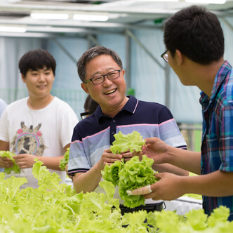 A man holding lettuce and smiling at a friend